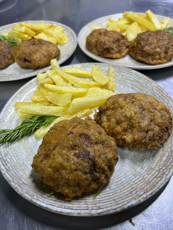 Three plates of fried meat patties with chips and rosemary
