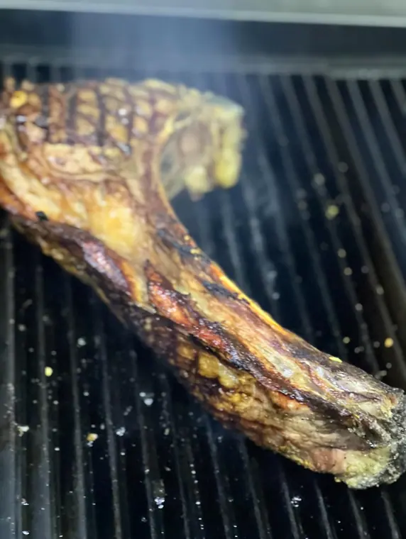 Tomahawk steak searing on a ribbed grill