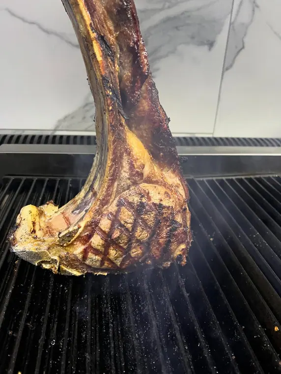 Tomahawk steak stood upright on a grill
