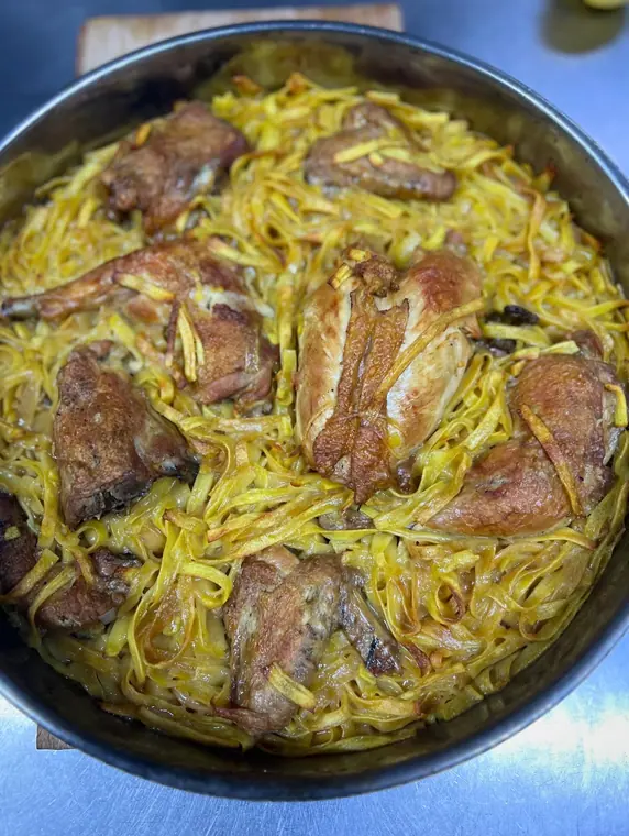 Tray of baked chicken pieces with yellow egg noodles