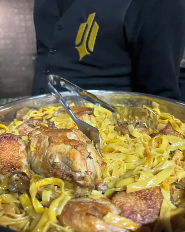Tray of chicken pieces with tagliatelle and serving tongs