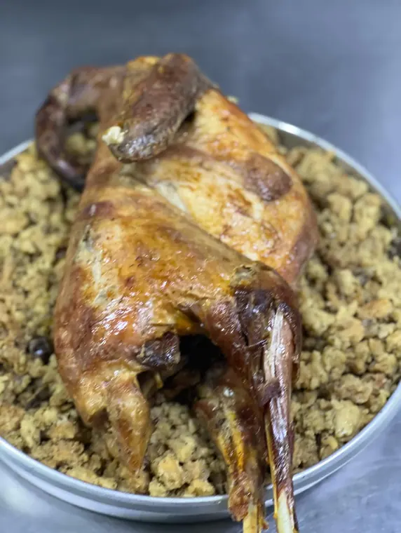 Whole roasted fowl on bread stuffing in metal tray