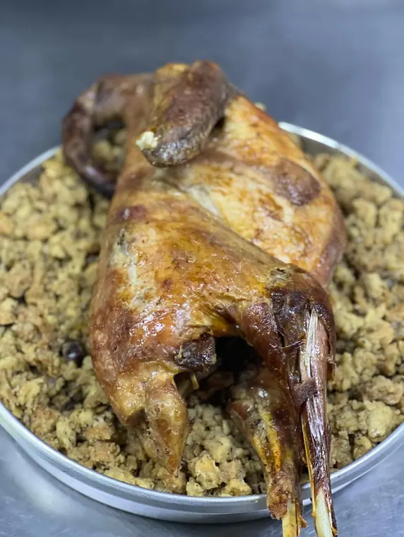 Whole roasted fowl on bread stuffing, legs over tray rim