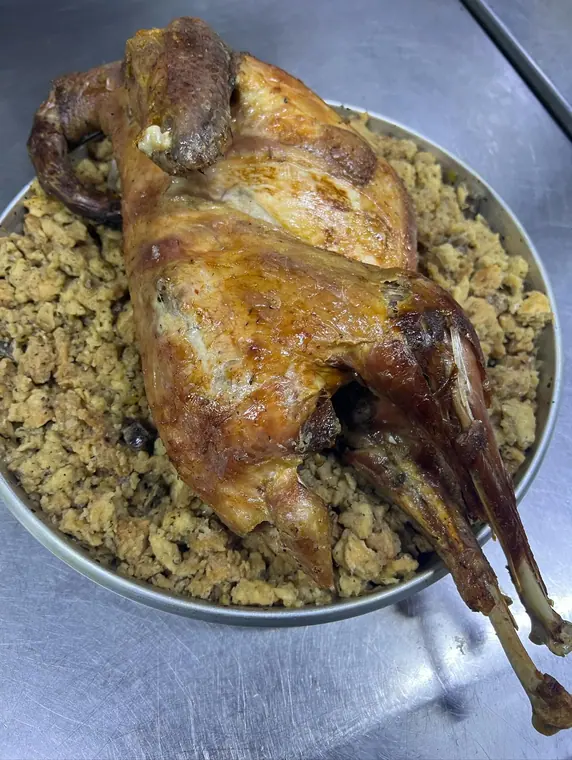Whole roasted fowl on bread stuffing on steel counter