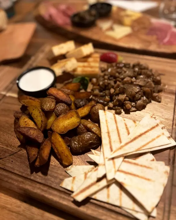 Wooden board with potato wedges, dip and grilled flatbread triangles