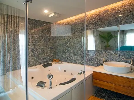 Corner jacuzzi tub in granite-clad bathroom with vessel basin