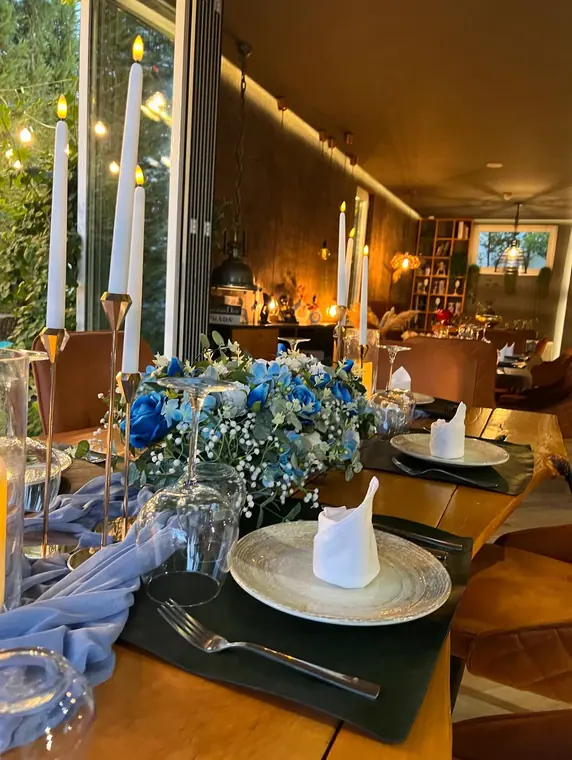 Candlesticks and blue rose centrepiece on set dining table