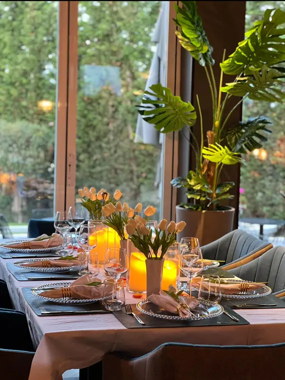 Evening table setting with tulips, candles and grey chairs by window
