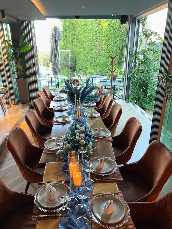 Long banquet table set with blue runner, roses and pampas