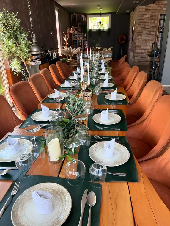 Long candlelit banquet table between rows of orange chairs