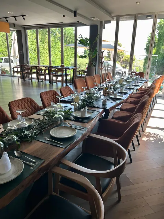 Long set table with row of orange chairs, sunlit dining room