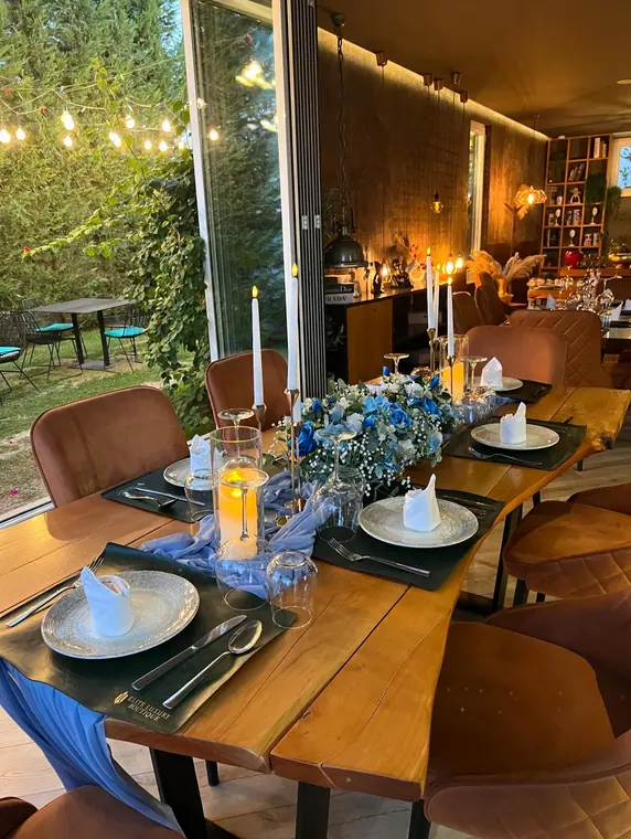 Long wooden table set with blue flowers and candles at dusk