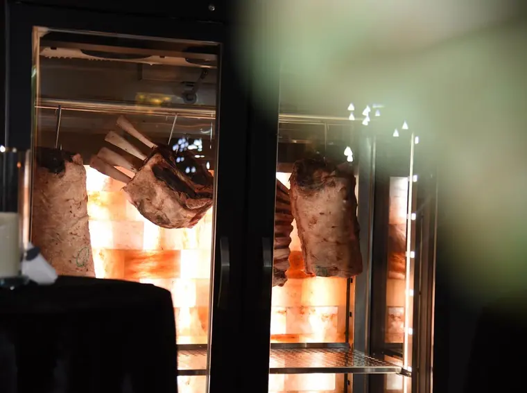 Racks of beef ageing in a salt-lit glass cabinet