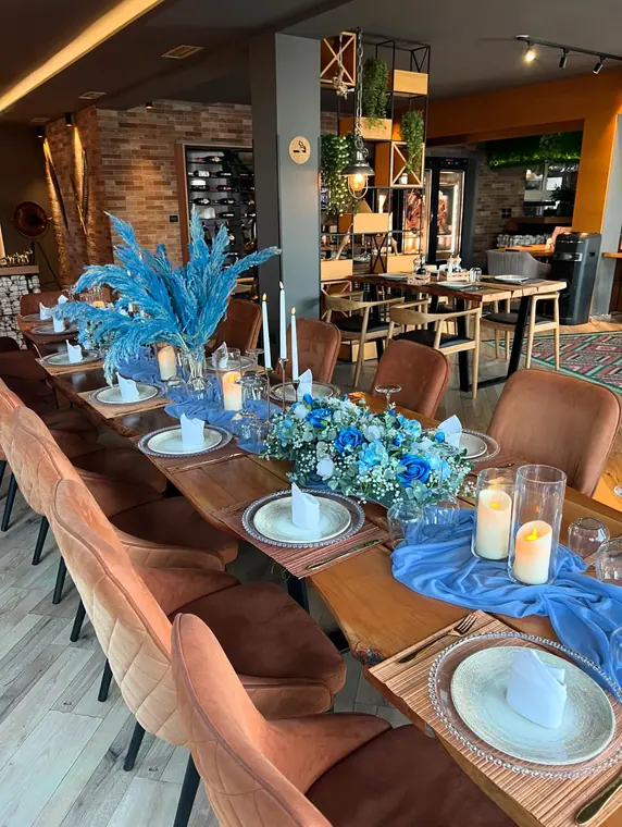 Set banquet table with blue pampas, seen across the dining room