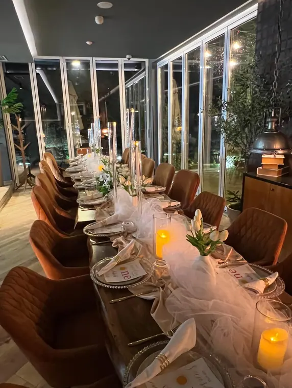 Set banquet table with candles and tulips beside glass doors at night