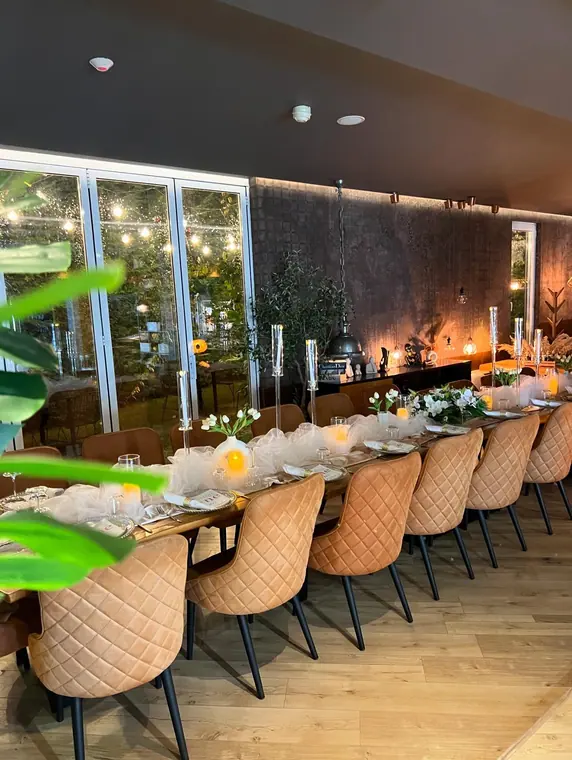 Set banquet table with tan chairs beside folding glass doors