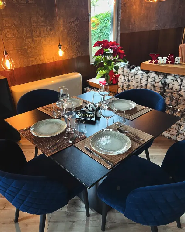 Square table set for four with blue velvet chairs and poinsettia