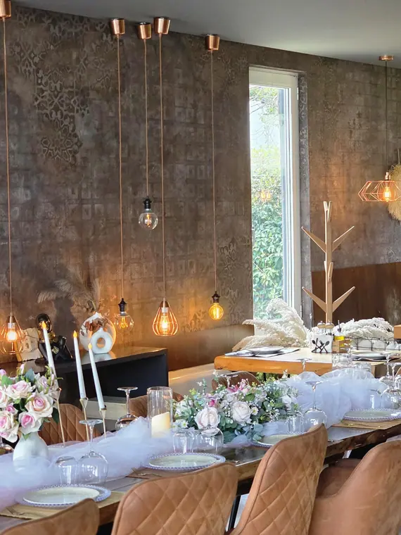 Textured wall with copper pendant lamps above dressed banquet table