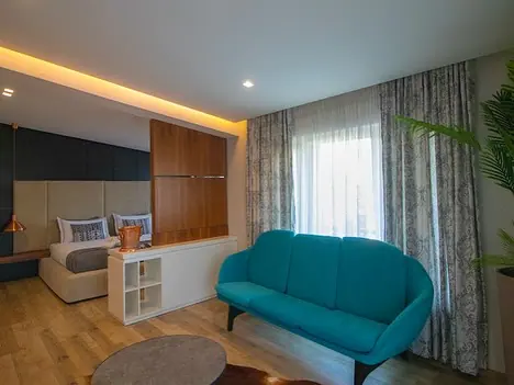 Bedroom with teal sofa, bed and curtained window