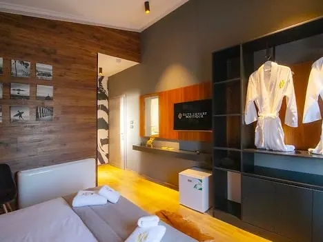 Bedroom with wall-mounted TV, minibar and two hanging robes