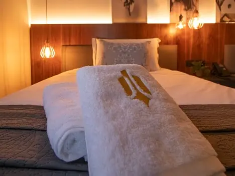 Folded white towels with gold logo on bed