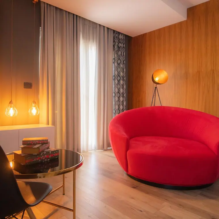 Room seating area with red round sofa, tripod lamp and glass table