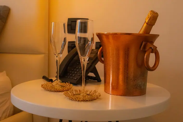Sparkling wine bottle in copper bucket with two flutes on bedside table