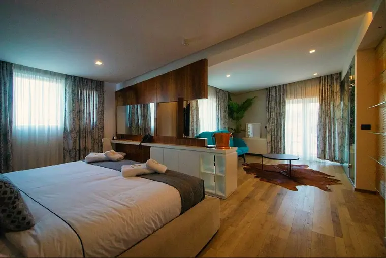 Suite with king bed, long wood desk unit, armchair and hide rug