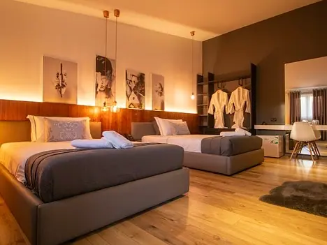 Twin-bed room with wall art, hanging robes, desk and wood floor
